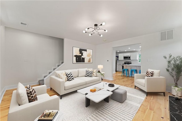 23 Saint Thomas St, South Side, PA 15203 - living area featuring light wood-style flooring, a chandelier, stairs, and baseboards