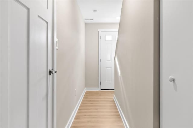 hallway featuring baseboards and light wood finished floors