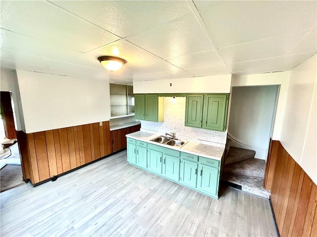 402 Vine St, South Connellsville, PA 15425 - kitchen with green cabinetry, a sink, light countertops, wainscoting, and light wood finished floors