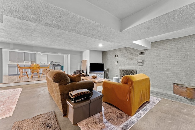 living room featuring finished concrete floors, a textured ceiling, a brick fireplace, and brick wall