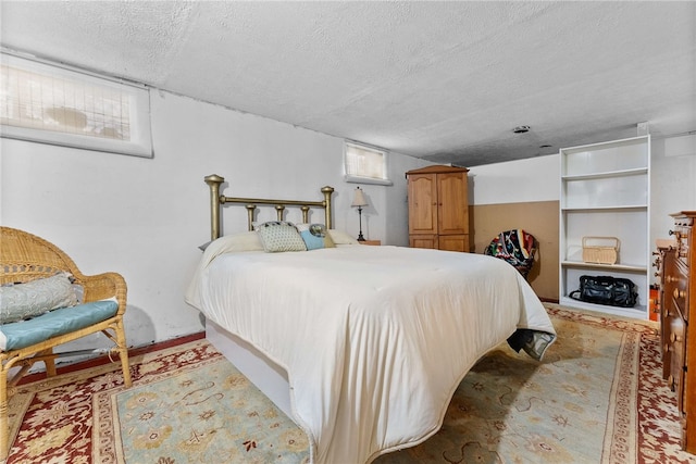 bedroom with a textured ceiling and multiple windows