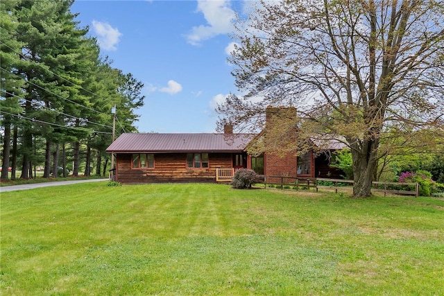 view of front of home featuring a chimney, a front yard, and metal roof