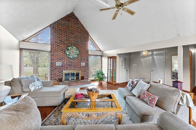 living room with high vaulted ceiling, ceiling fan, wood finished floors, a brick fireplace, and a textured ceiling