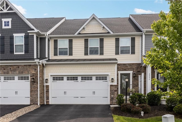 townhome / multi-family property featuring stone siding, asphalt driveway, an attached garage, and a shingled roof