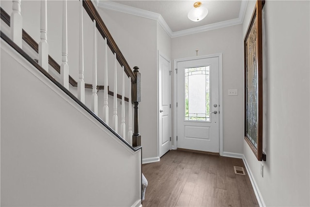 foyer with wood finished floors, ornamental molding, stairs, and baseboards