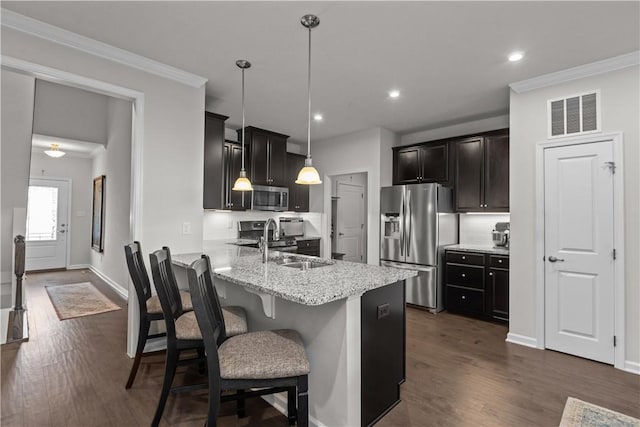 kitchen with appliances with stainless steel finishes, a sink, a peninsula, light stone countertops, and a breakfast bar area