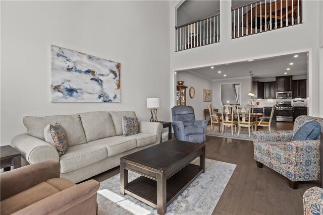 living area with dark wood-style floors, a high ceiling, and recessed lighting