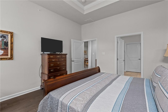 bedroom with wood finished floors, baseboards, and crown molding