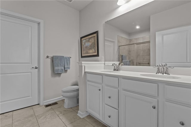 bathroom featuring a stall shower, double vanity, toilet, tile patterned flooring, and baseboards