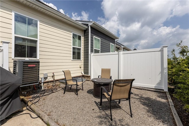 view of patio with central AC unit, fence, and a fire pit