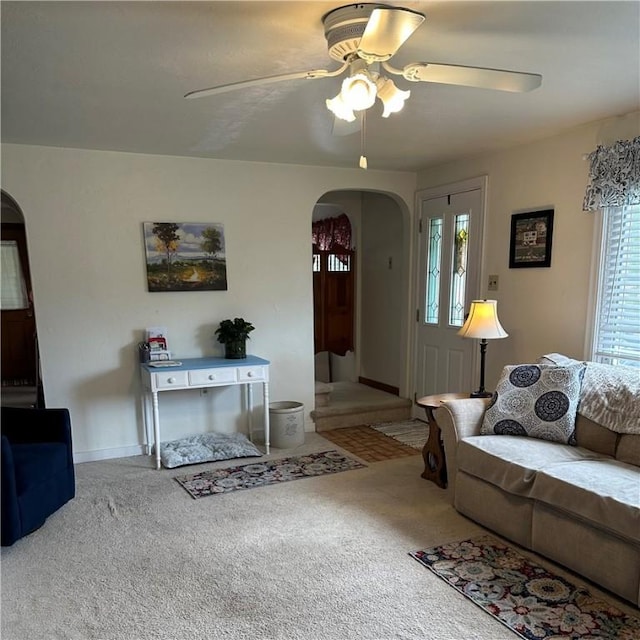 carpeted living room with arched walkways, plenty of natural light, and ceiling fan