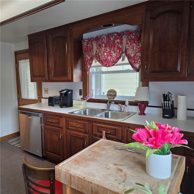 kitchen featuring stainless steel dishwasher, light countertops, and a sink