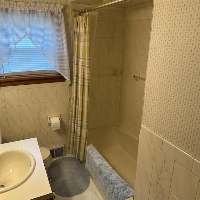 full bathroom featuring tile walls, wallpapered walls, shower / bath combo, toilet, and vanity