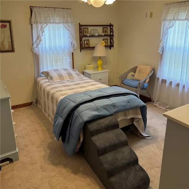 bedroom with light colored carpet and baseboards