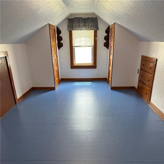 additional living space with a textured ceiling, lofted ceiling, baseboards, and tile patterned floors