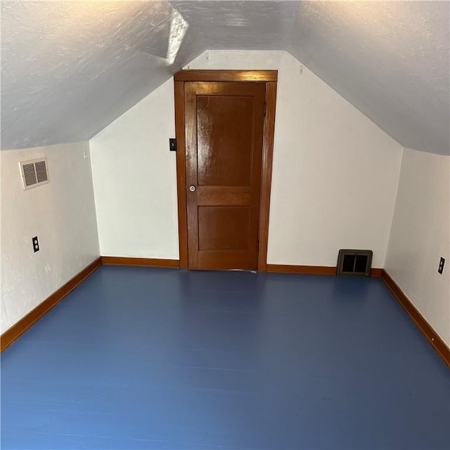 additional living space with lofted ceiling, baseboards, and a textured ceiling