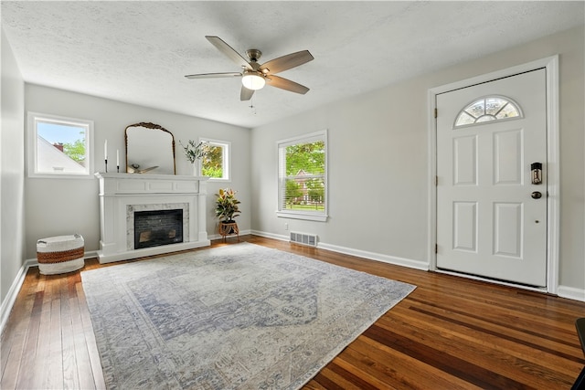 living area featuring dark wood finished floors, a ceiling fan, a premium fireplace, and baseboards
