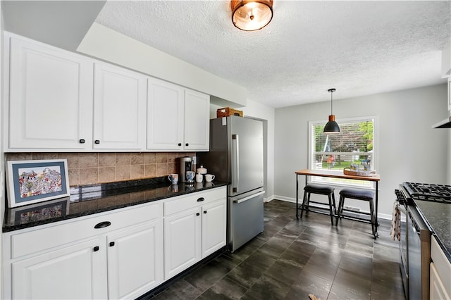 kitchen featuring stainless steel appliances, decorative backsplash, a textured ceiling, white cabinets, and baseboards