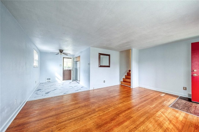 815 Londonderry Dr, Castle Shannon, PA 15234 - unfurnished living room featuring light wood-type flooring, stairs, a ceiling fan, baseboards, and a textured ceiling