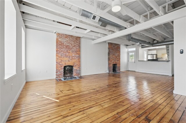 5111 Penn Ave, Garfield, PA 15224 - unfurnished living room with a brick fireplace, hardwood / wood-style flooring, ceiling fan, beamed ceiling, and baseboards