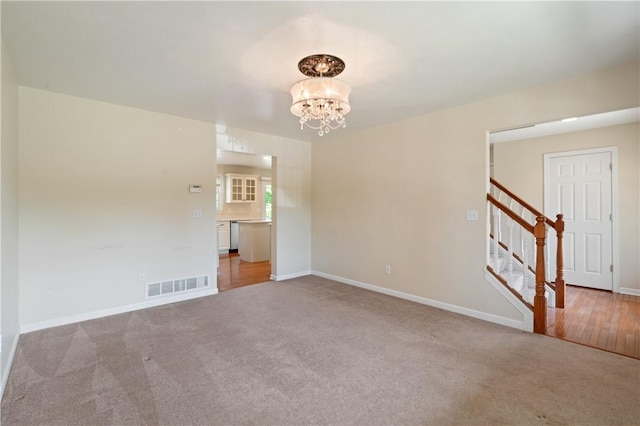 carpeted spare room with a chandelier, stairs, and baseboards