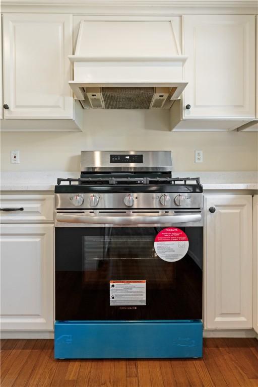 kitchen featuring gas stove, premium range hood, light countertops, and white cabinetry