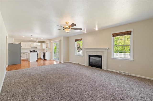 unfurnished living room with baseboards, a fireplace, ceiling fan, light carpet, and recessed lighting