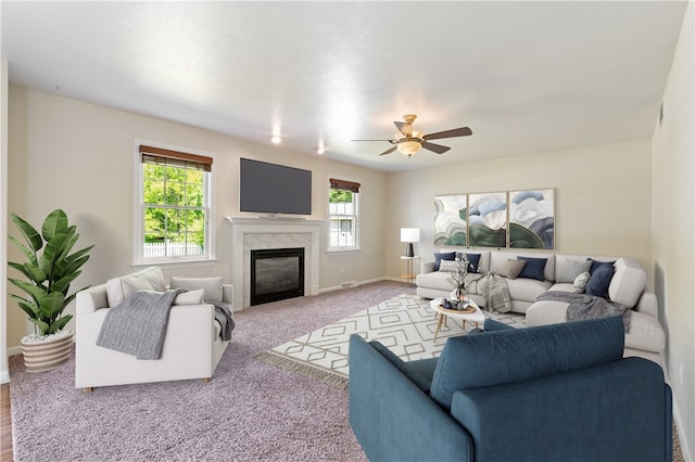 carpeted living area featuring a ceiling fan, a glass covered fireplace, and baseboards