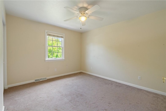 carpeted empty room featuring a ceiling fan and baseboards