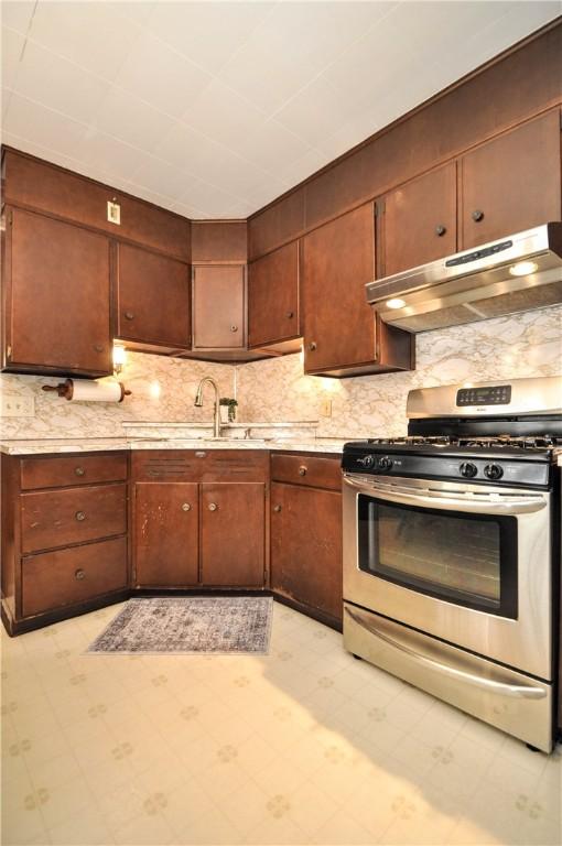 24 N St, Smith, PA 15004 - kitchen featuring stainless steel gas range, under cabinet range hood, a sink, light flooring, and tasteful backsplash