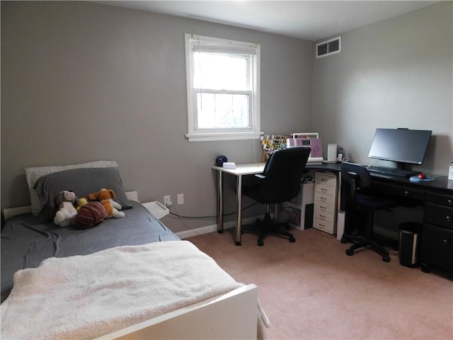 bedroom featuring an office area and light colored carpet