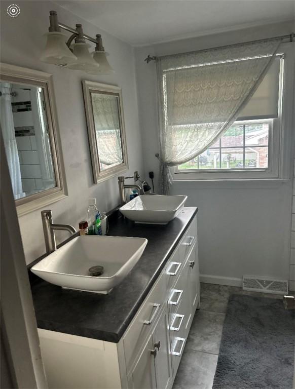 full bath featuring double vanity, baseboards, and tile patterned flooring