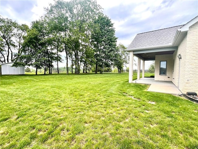 view of grassy yard with a patio area, an outbuilding, and a storage shed