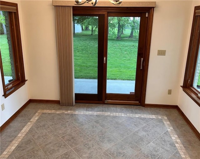 entryway featuring baseboards, inlaid floor details, a chandelier, and tile patterned flooring