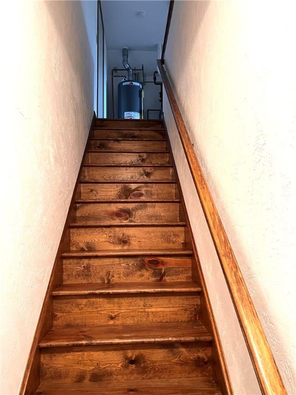 stairs with water heater and a textured wall