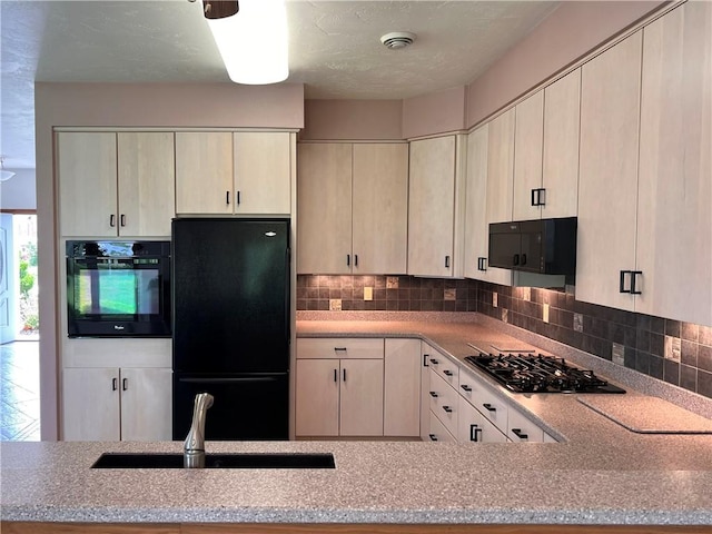 kitchen with black appliances, a sink, decorative backsplash, and light stone countertops