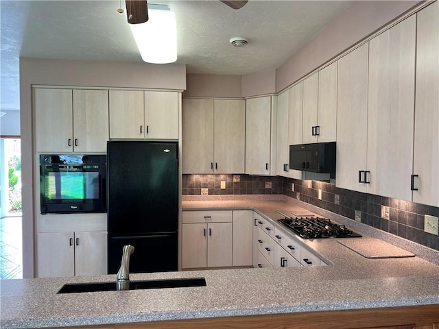 kitchen with black appliances, a sink, decorative backsplash, and light stone counters