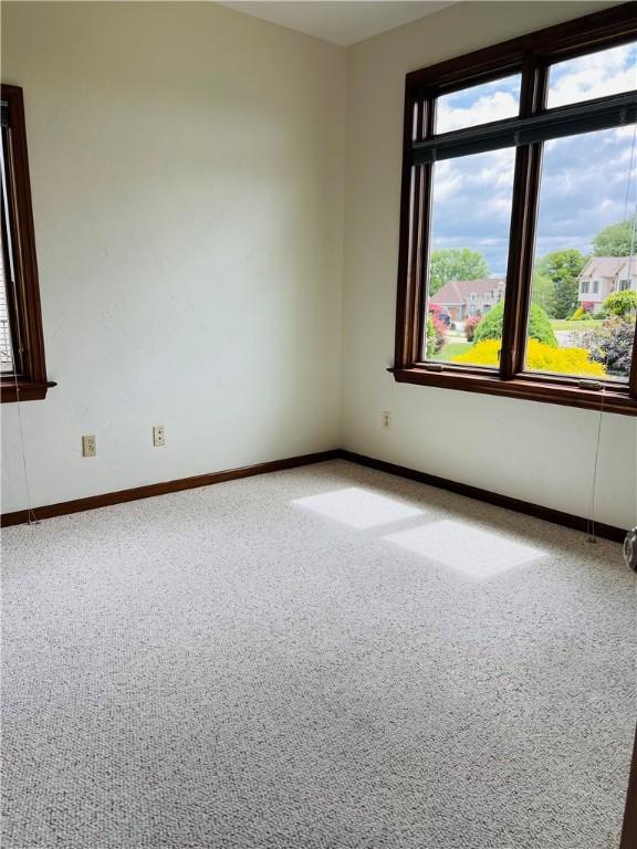 carpeted empty room featuring baseboards