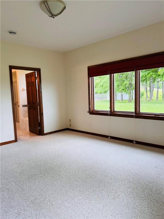unfurnished room featuring baseboards and light carpet