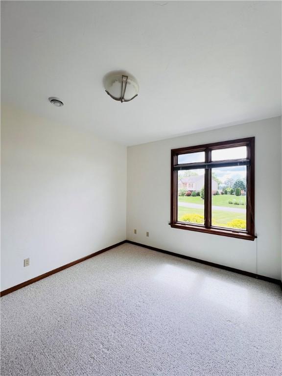 carpeted spare room featuring baseboards