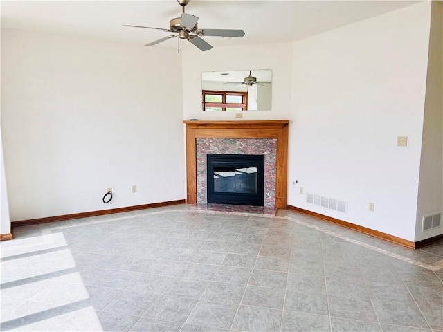 unfurnished living room with a ceiling fan, a tile fireplace, tile patterned floors, and baseboards