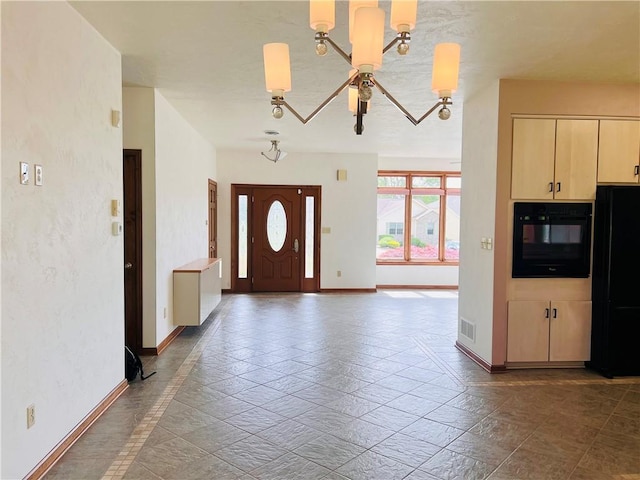 entryway with a chandelier, baseboards, and stone tile floors