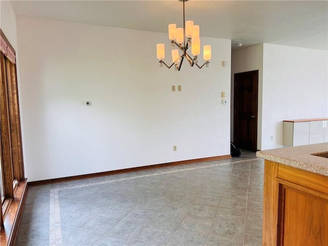unfurnished dining area featuring a chandelier and baseboards