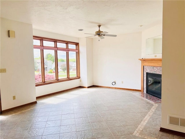 unfurnished living room featuring baseboards, a ceiling fan, and a tile fireplace