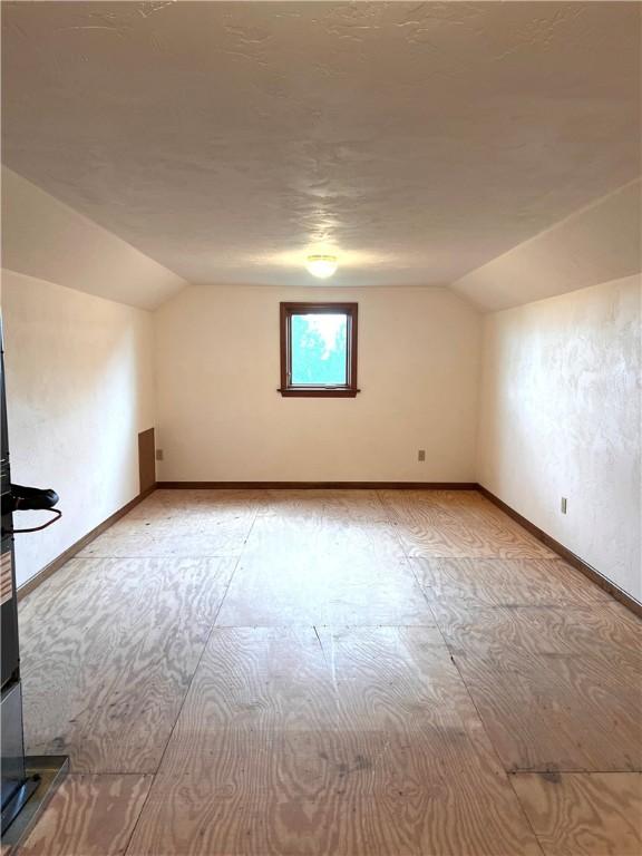additional living space featuring lofted ceiling and baseboards