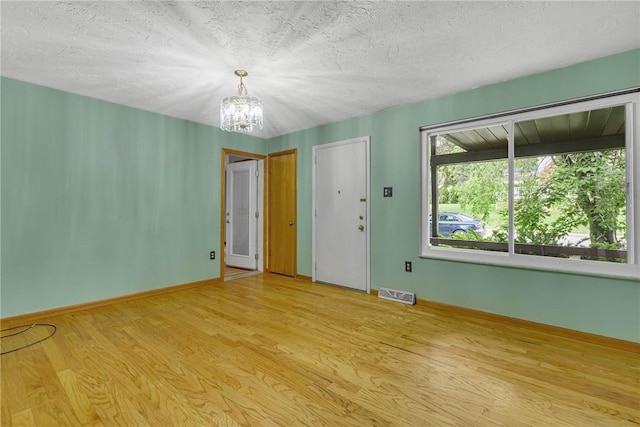 907 3rd St, Baden, PA 15005 - spare room with a chandelier, light wood-style floors, baseboards, and a textured ceiling