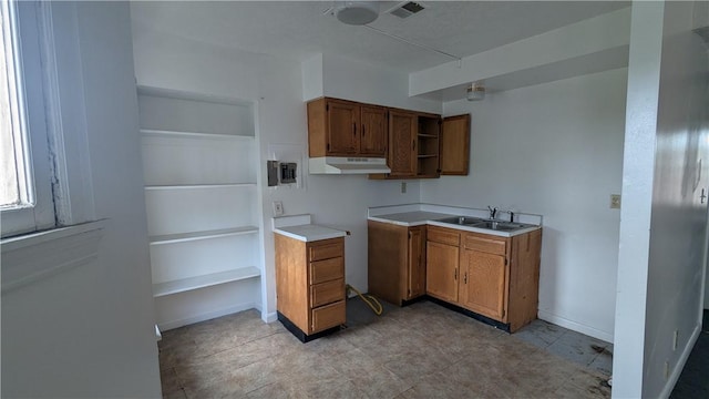 315 Lowell St, East Liberty, PA 15206 - kitchen with under cabinet range hood, brown cabinetry, a sink, open shelves, and baseboards