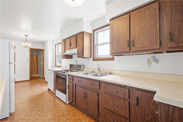 106 Level St, Bentleyville, PA 15314 - kitchen with white appliances, under cabinet range hood, light countertops, a chandelier, and brown cabinetry