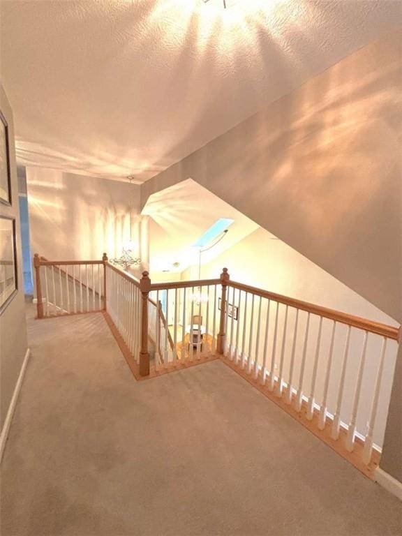 hallway with carpet flooring, an upstairs landing, and baseboards