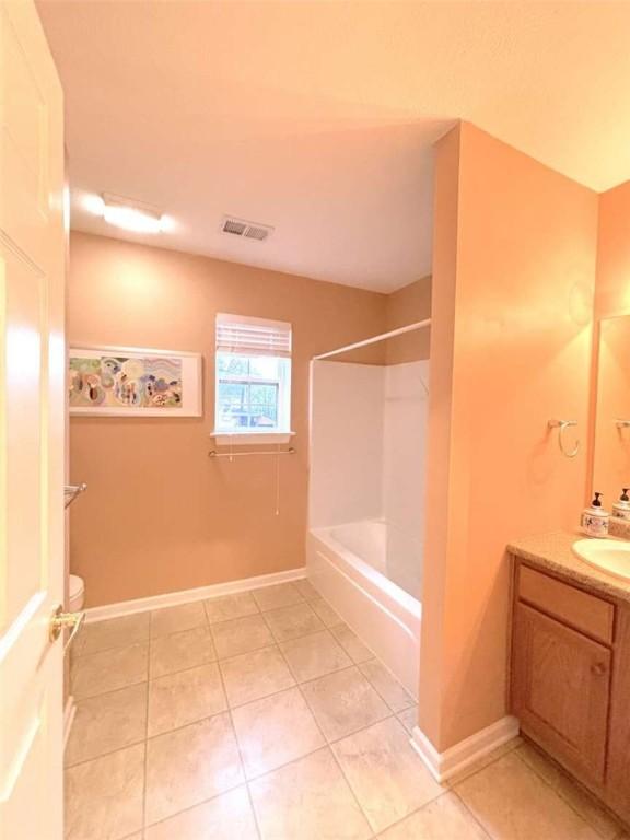 full bathroom with tile patterned flooring, vanity, baseboards, tub / shower combination, and toilet